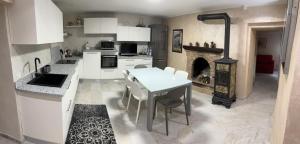 a kitchen with white cabinets and a table and a fireplace at IL NIDO DELLA POIANA CASA VACANZE e B & B in Montalto Pavese