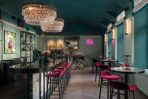 - un bar avec des tables et des chaises dans une pièce aux murs verts dans l'établissement Falkensteiner Boutique Hotel Prague, à Prague