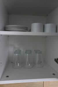 a kitchen shelf with four glass dishes and plates at FORUM apartmani i sobe in Donji Miholjac