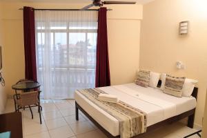 1 dormitorio con 1 cama y ventana grande en Merry Villa Hotel & Apartments, en Mombasa