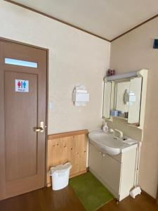 La salle de bains est pourvue d'un lavabo, d'un miroir et de toilettes. dans l'établissement Azumino Backpackers, à Matsukawa