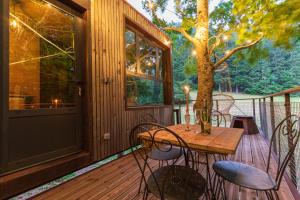 - une terrasse couverte avec une table et des chaises en bois dans l'établissement Cabane perchée La Résilience sur le plateau du Vercors, à Autrans