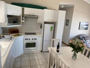 a kitchen with white cabinets and a table with flowers on it at Herolds Bay Accommodation - Hiers Ons Weer Upstairs in Herolds Bay