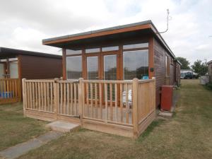 a small cabin with a porch and a fence at Beautiful 2-Bed Chalet in Mablethorpe in Mablethorpe