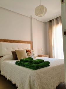 a green blanket sitting on top of a bed at House Parra in San Juan de los Terreros