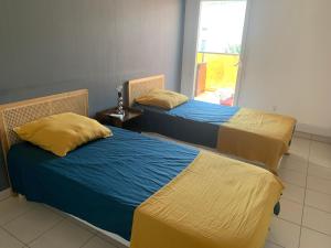 - 2 lits avec des draps jaunes et bleus dans une chambre dans l'établissement Bel appartement neuf climatisé & parking, à Perpignan