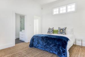 a white bedroom with a bed with a blue blanket at Secure & Central: Villa with Views of Table Mountain in Cape Town