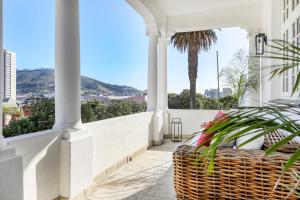 einen Korbkorb auf einer weißen Veranda mit einem Balkon in der Unterkunft Secure & Central: Villa with Views of Table Mountain in Kapstadt