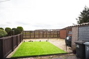 een kleine achtertuin met een hek en een groen gazon bij Rigside House in Douglas