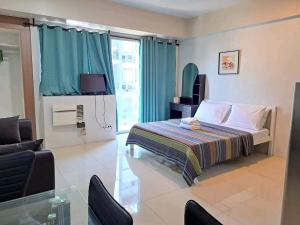 een slaapkamer met een bed, een bank en een televisie bij MRMcondotel in Manilla