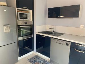 een keuken met een wastafel en een magnetron bij Bel appartement neuf climatisé & parking in Perpignan