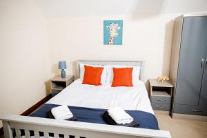 1 dormitorio con cama blanca y almohadas de color naranja en Rigside House, en Douglas
