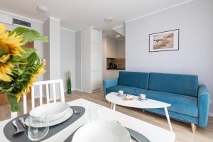 un salon avec un canapé bleu et une table dans l'établissement Little Laguna Apartments SPA & Gym by Noclegi Renters, à Międzywodzie