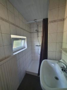 a bathroom with a sink and a shower and a tub at 't Schoenmakershuisje in Epen