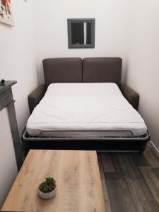 a bed in a room with a wooden table and a bed sidx sidx at Appart cosy avec balnéo, balcon, clim à 15 min de la Cité in Carcassonne