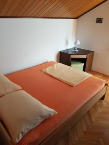 a bed with an orange blanket and a desk in a room at Apartments Celine & Fabienne in Brodarica