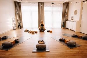 une femme est assise dans une pose de yoga dans une pièce dans l'établissement Okelmann's - Entspannte Achtsamkeit - Bewusster Lifestyle, à Warpe