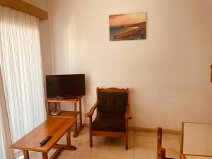 een kamer met een stoel, een tafel en een televisie bij Kaan Hotel & Apartment in Kyrenia