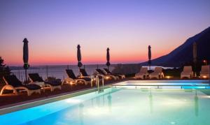 a pool with chairs and a sunset in the background at Pantheon Hotel & Suites in Nerotriviá