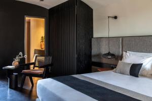 a bedroom with a bed and a chair and a table at Nimbus Santorini in Oia
