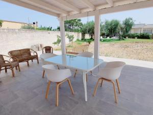 a glass table and white chairs on a patio at Villa Talìa in Marsala