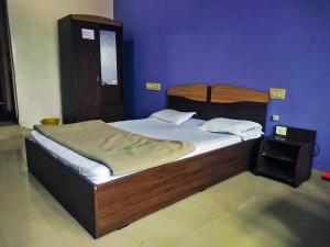 a bed in a bedroom with a blue wall at STAYMAKER Pushpagiri Comforts in Sakleshpur