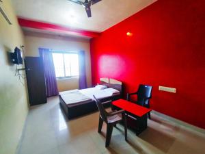 a red room with a bed and a table and chairs at STAYMAKER Pushpagiri Comforts in Sakleshpur