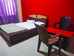 a bedroom with a bed and a desk and a chair at STAYMAKER Pushpagiri Comforts in Sakleshpur