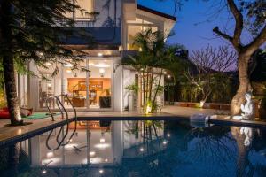 une piscine devant une maison la nuit dans l'établissement El Cottage by StayVista - An enchanting escape with Scenic views, Colonial decor & Private plunge pool, à Lonavala