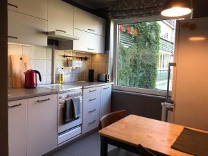 a kitchen with white cabinets and a table and a window at Cosy Teika Apartment in Rīga