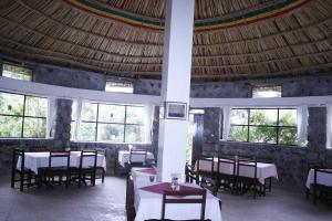 a restaurant with tables and chairs in a room with windows at Jerusalem Hotel Lalibela in Lalibela