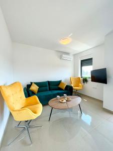 sala de estar con sofá verde y sillas amarillas en J&N Hill's Residence with swimming pool, en Medulin