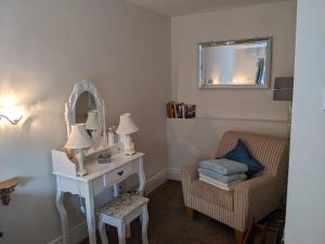 a room with a table and a mirror and a chair at Granary Cottage in Mickleton
