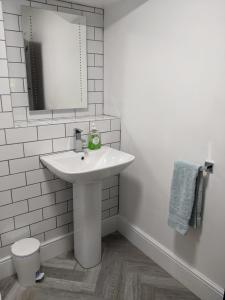 a white bathroom with a sink and a mirror at Granary Cottage in Mickleton