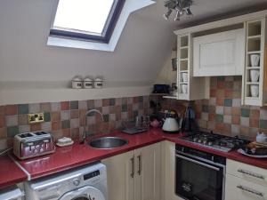 a kitchen with a sink and red counter top at Granary Cottage in Mickleton