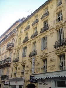un gran edificio amarillo con un cartel. en Hôtel du Petit Louvre, en Niza
