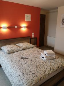 - une chambre dotée d'un lit avec un mur orange dans l'établissement L'auberge des quatre routes, à Albussac