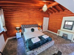 a bedroom with a bed and a wooden wall at Kaoglen-Blossom-Hot tub-Cairngorms-Pet Friendly in Balnald