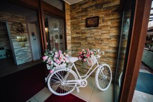 a white bike parked next to a brick wall with flowers in baskets at Pensiunea Bello in Marghita