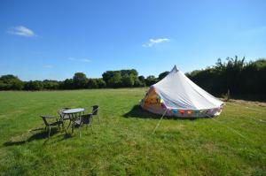 a tent and two chairs and a table in a field at Starlight Glamping 