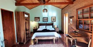 a bedroom with a bed and a wooden wall at Hospedaria Aikó in São Bento do Sapucaí