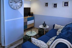 a living room with a blue couch and a clock at La Bulle Bleue futuroscope in Chasseneuil-du-Poitou