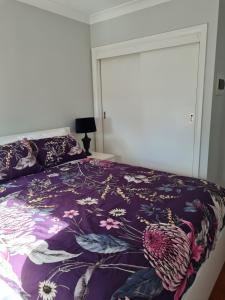 a bedroom with a bed with a purple comforter at Alkion Villa in Wagga Wagga