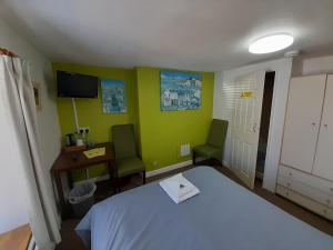 a bedroom with a bed and a desk and a tv at Globe Guesthouse in Burry Port