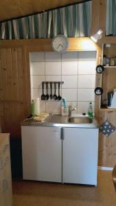 eine Küche mit einem Waschbecken und einer Uhr an der Wand in der Unterkunft Gartenhaus Haufe in Quedlinburg