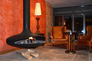 a fireplace in a room with two chairs and a table at Ringhotel Alpenhof - Patchworkhotel in Augsburg