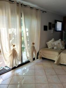 Schlafzimmer mit einem Bett und einem Fenster mit Vorhängen in der Unterkunft Casa massy in Arzachena