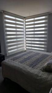 サンティアゴにあるDepartamento en el Corazon de Providenciaのベッドルーム1室(ベッド1台、大きな窓2つ付)