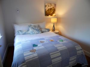 a bedroom with a bed with a blue and white quilt at Signature - Campsie Cottage in Glasgow