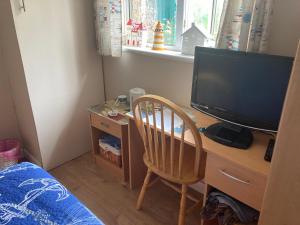 a bedroom with a desk with a television and a chair at Cove Cott in Warsash